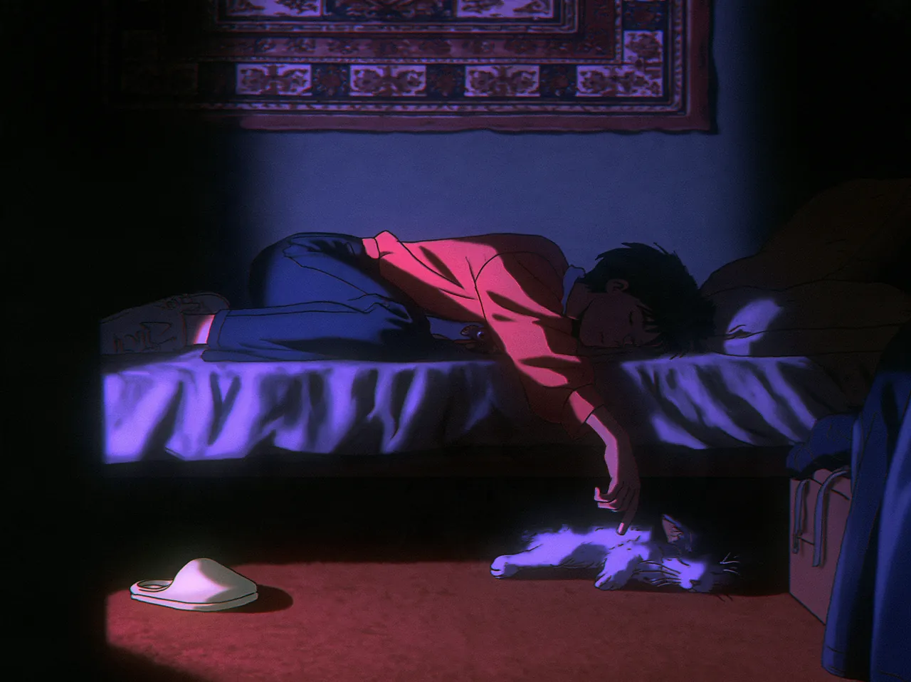 A young man asleep on his bed in the dark, one arm hanging down to the cat on the floor, a slipper by the bed